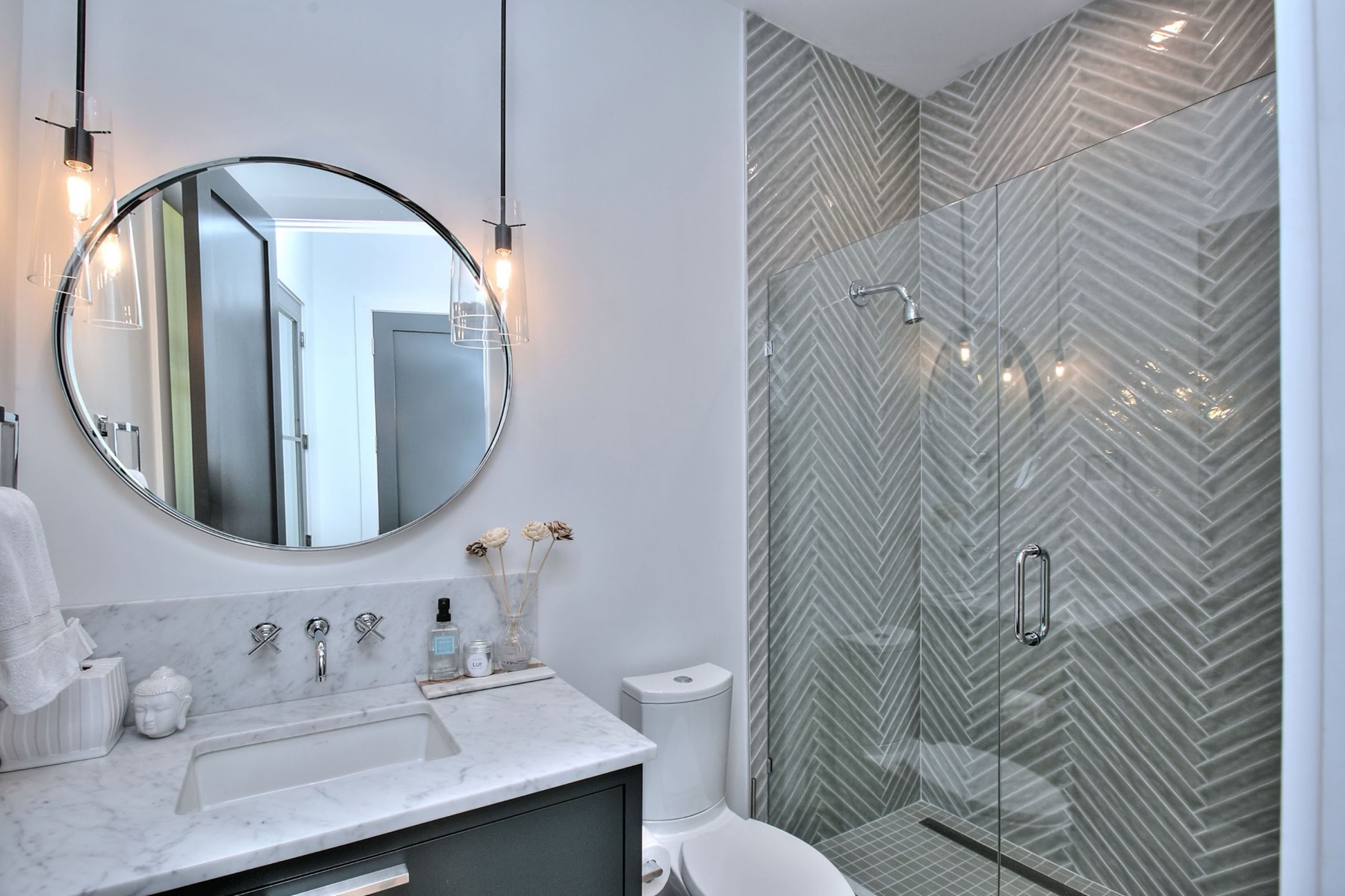 Herringbone tile shower and round mirror