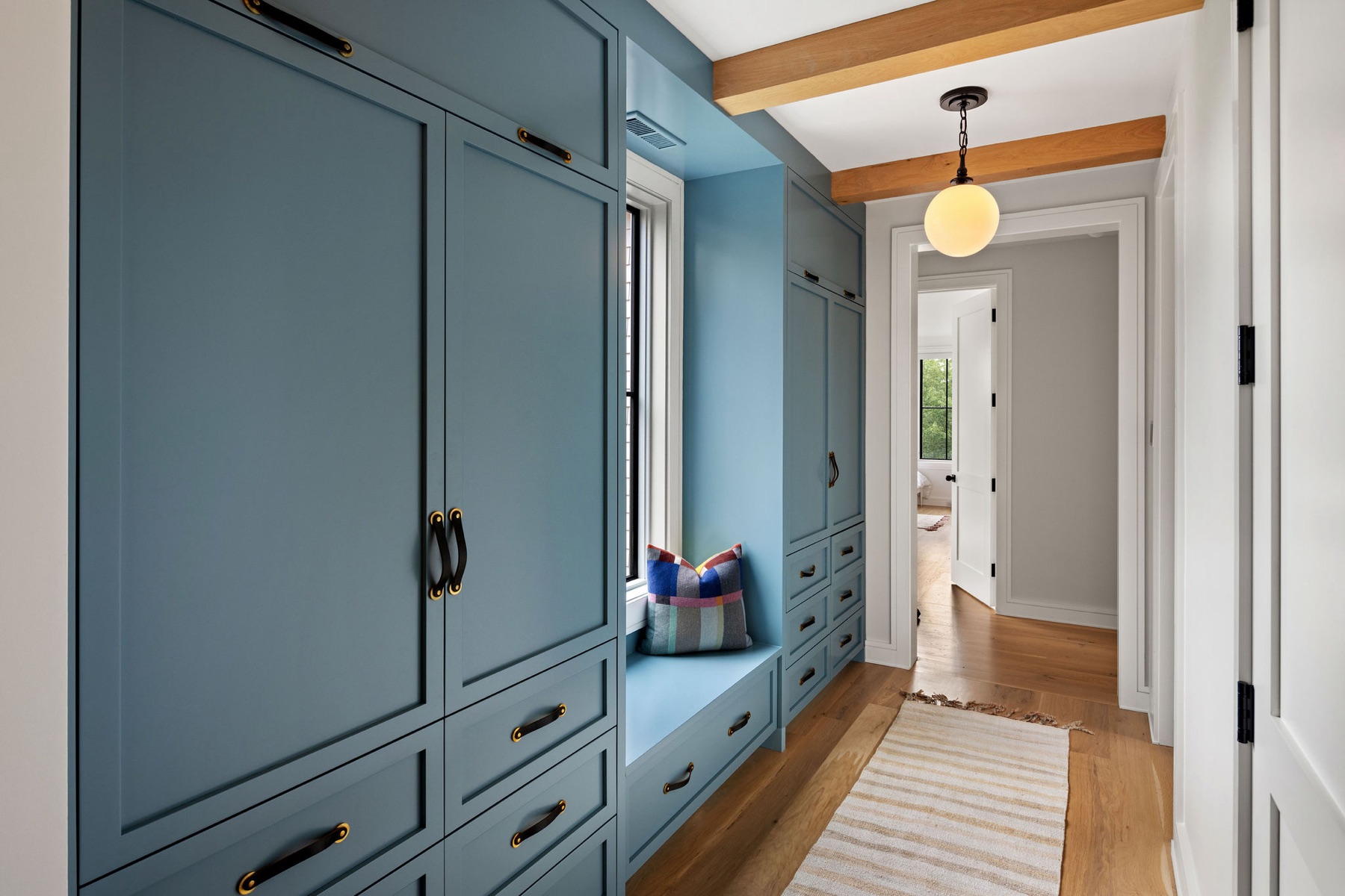 Blue cabinetry and a bench in a mudroom